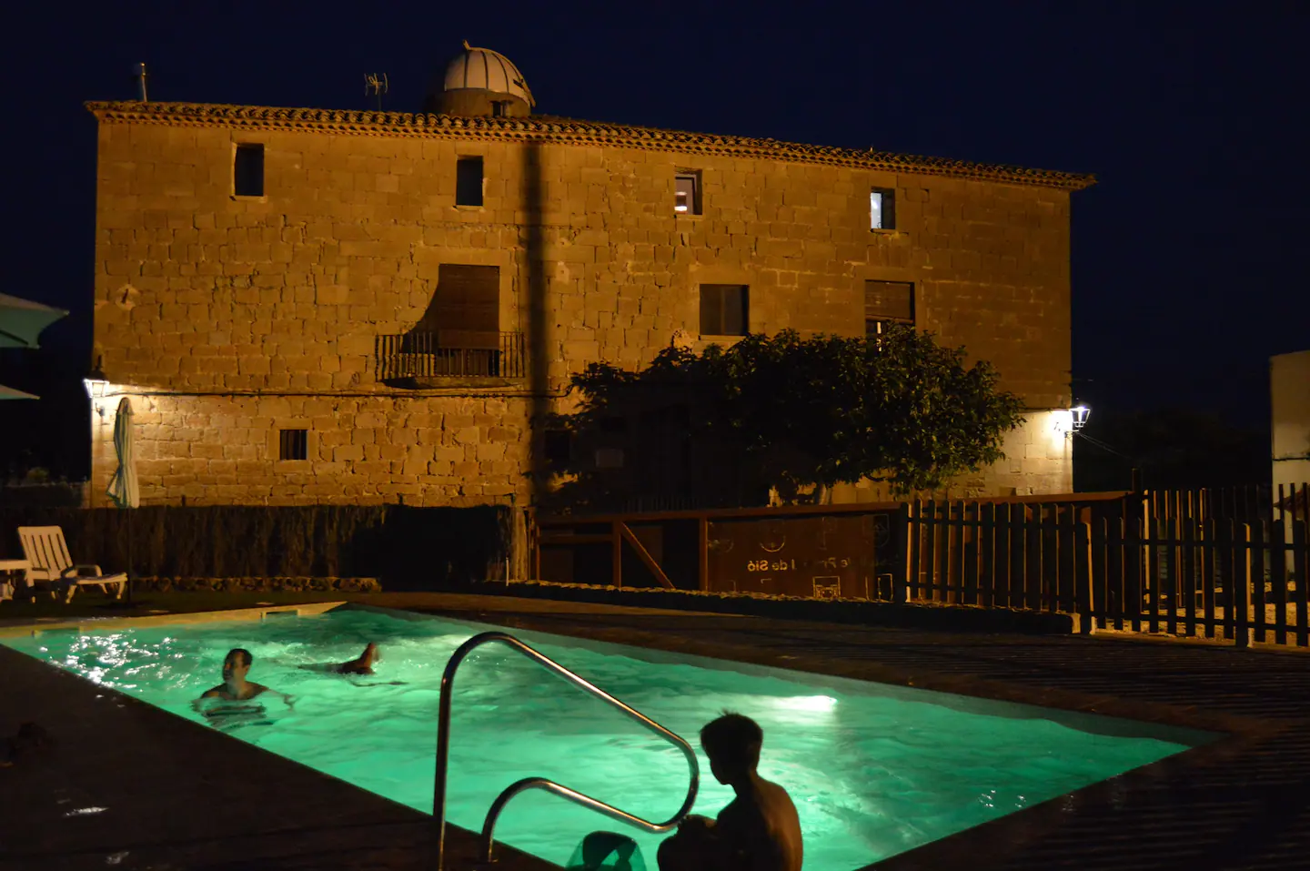 Imatge de la piscina del Castell del Pradell amb gent banyant-se durant la nit.